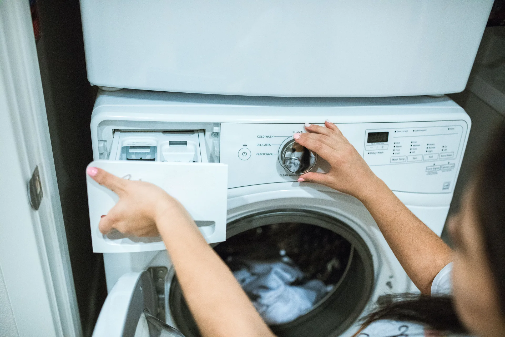 A person setting the controls on a front-load washing machine