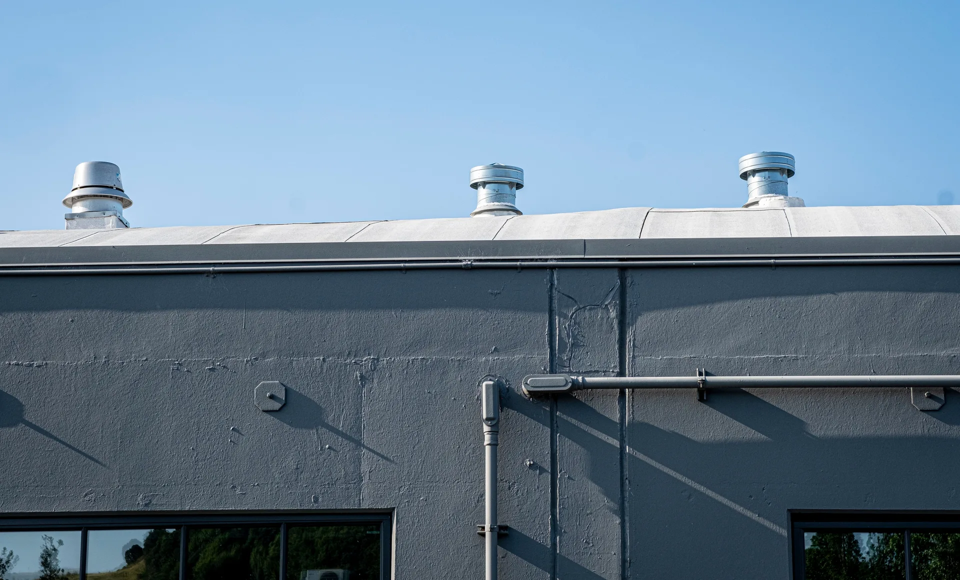 Rooftop vents on a gray building under a clear sky