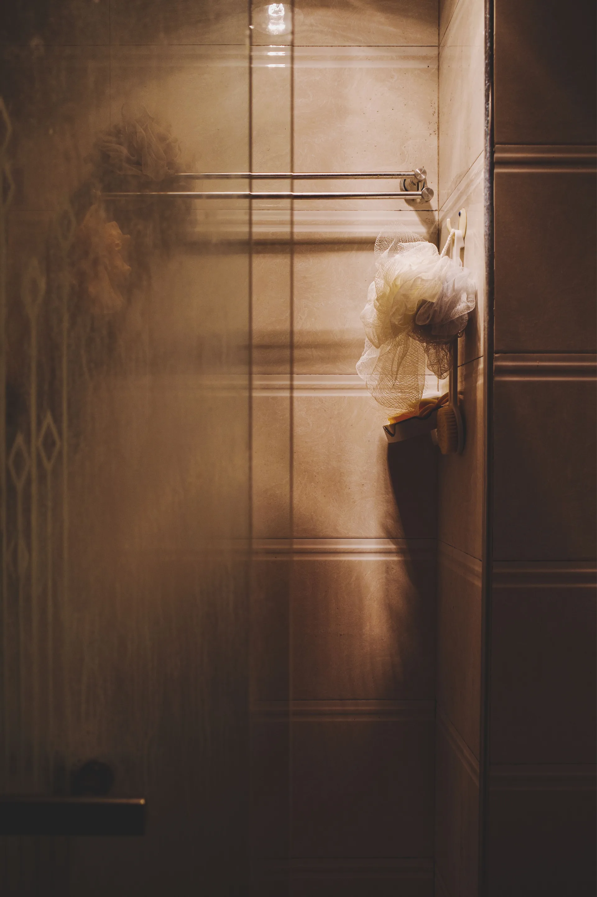 A bathroom with a shower, wooden wall panels, and soft light
