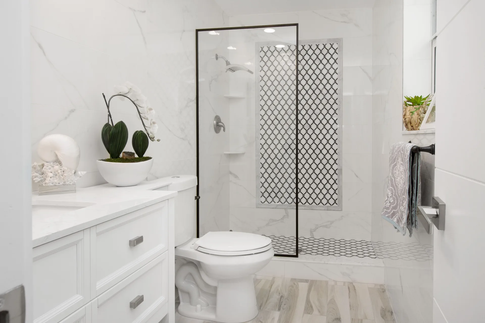 A bright white bathroom with a glass shower, sink, and toilet