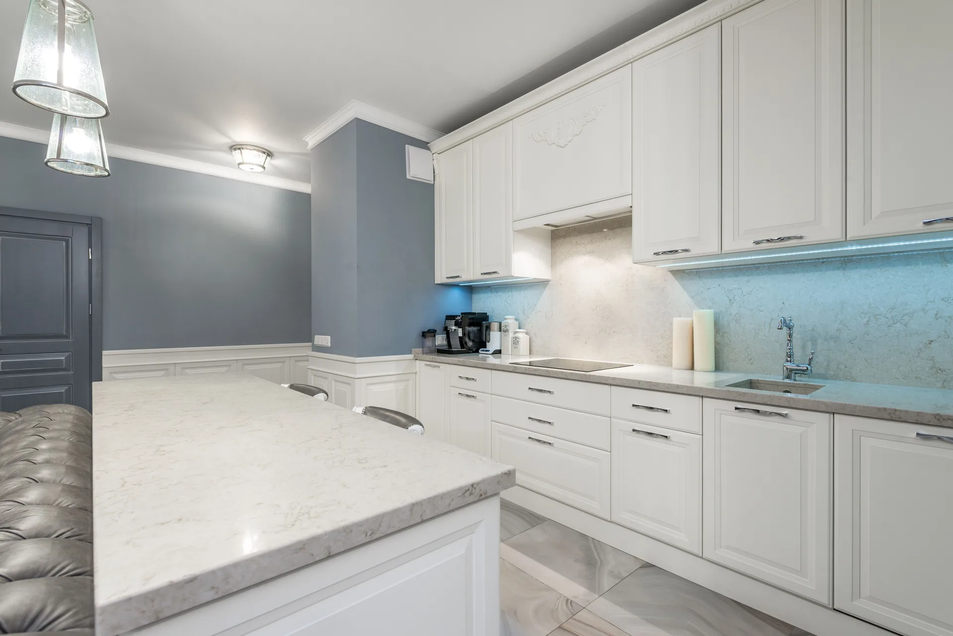 A modern kitchen with white cabinets and a marble counter