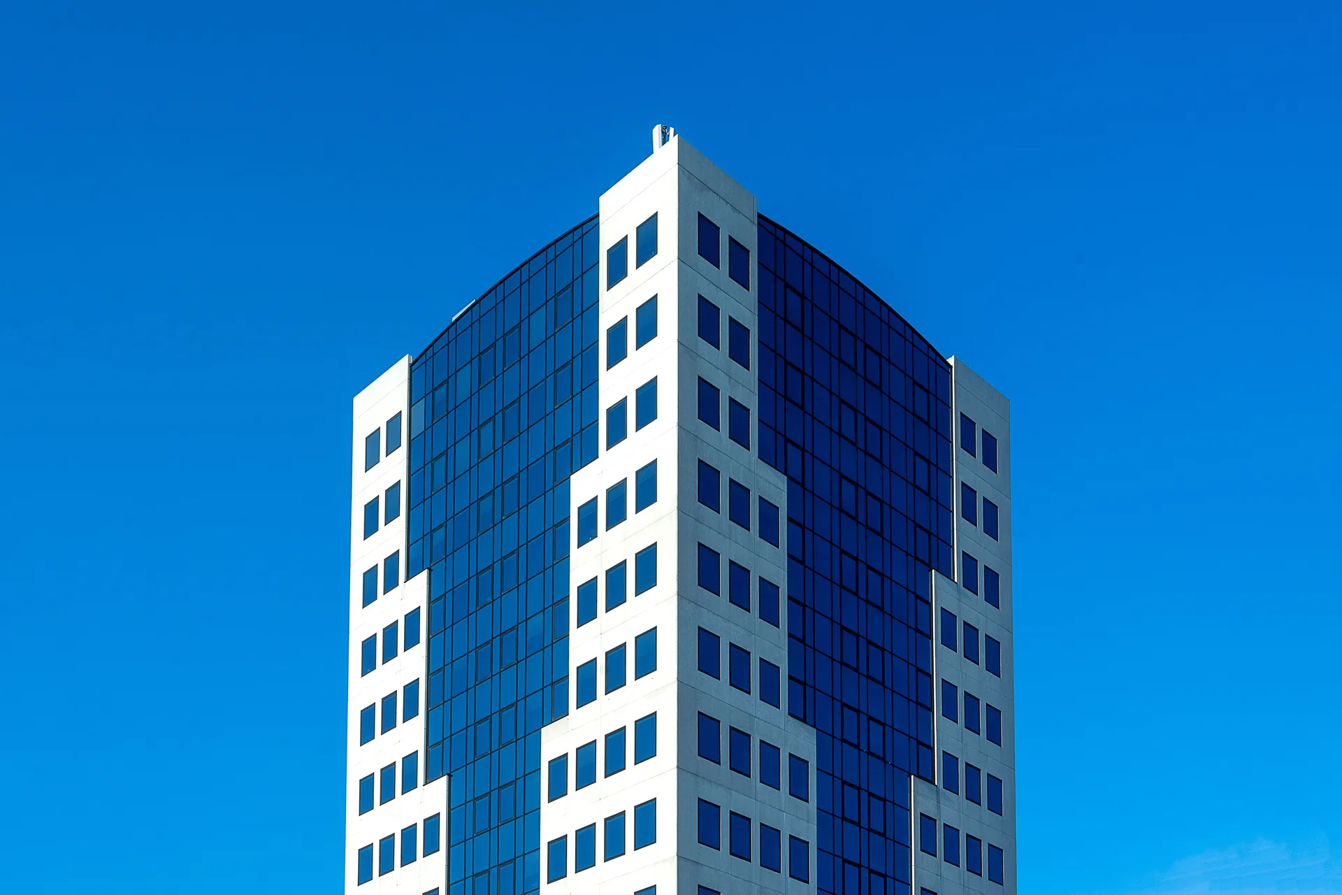 A tall office building with reflective windows against a blue sky