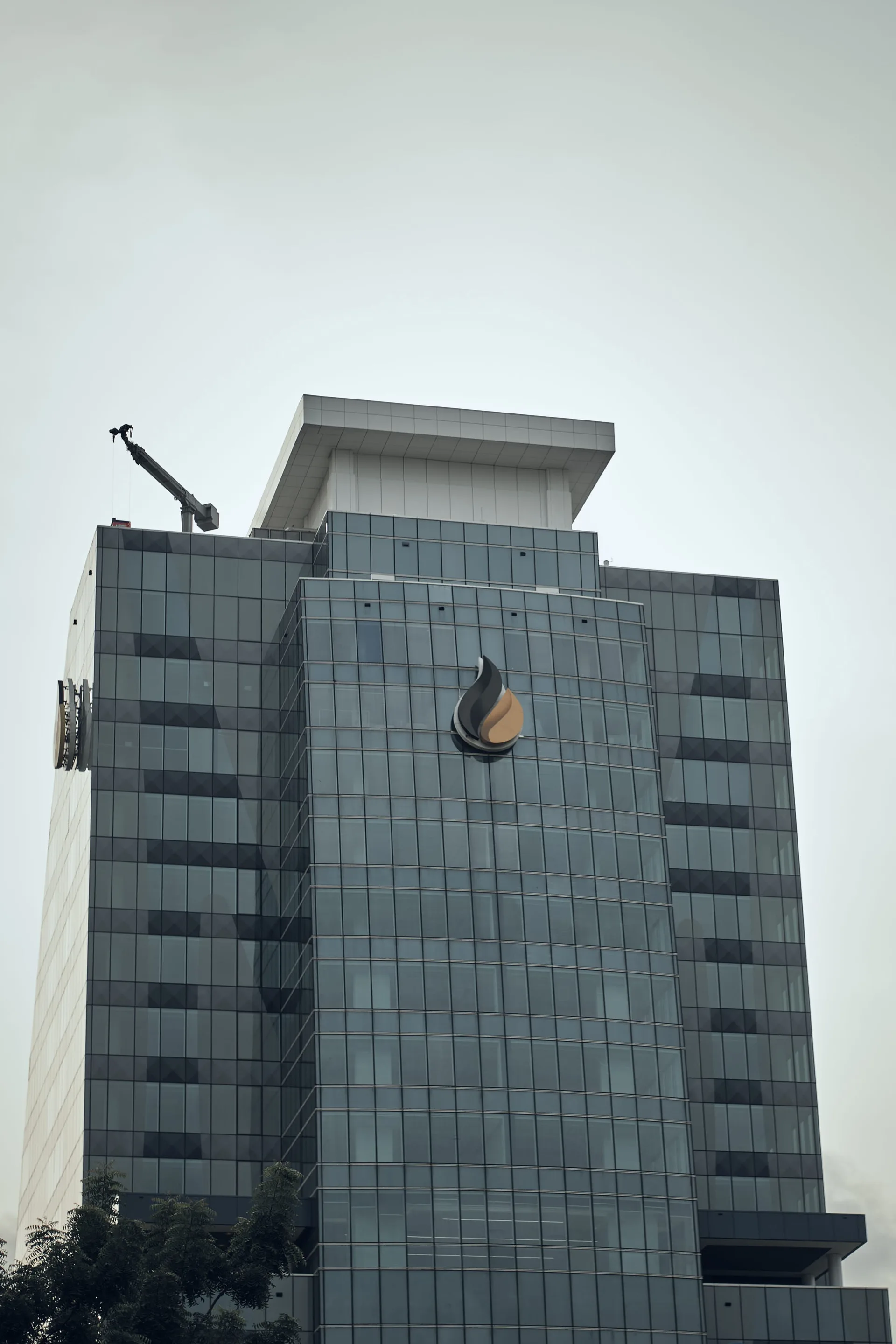 A glass-fronted modern office tower under a cloudy sky