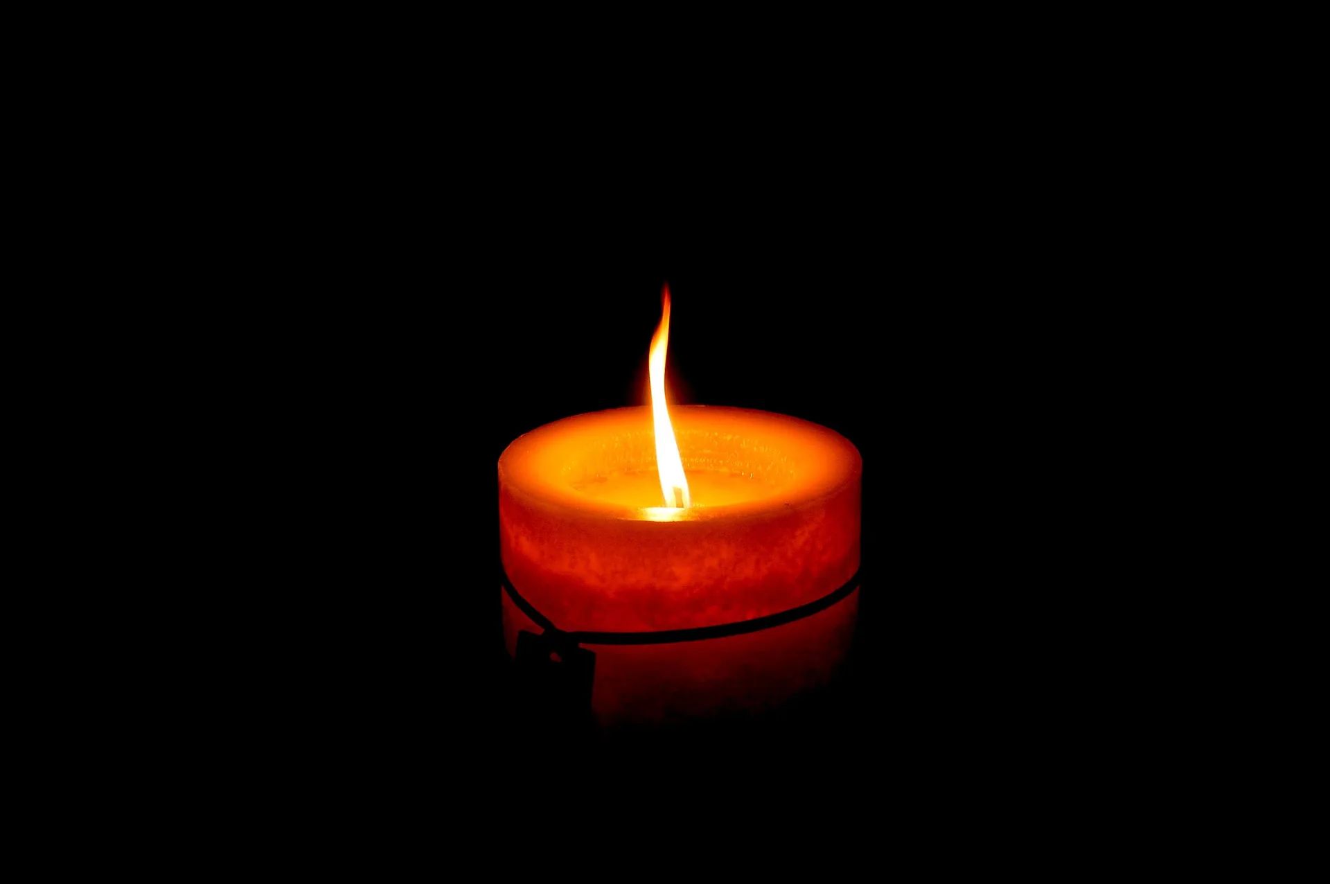A single candle flame glowing in a dark room
