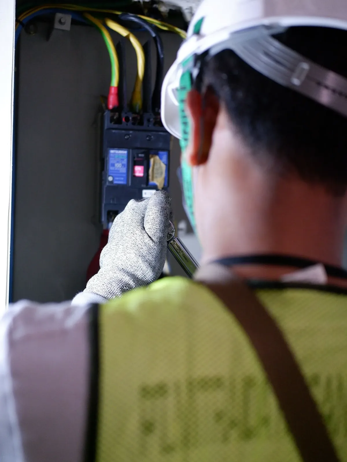 Male electrician in a hard hat and gloves working inside a breaker box in Fort Pierce