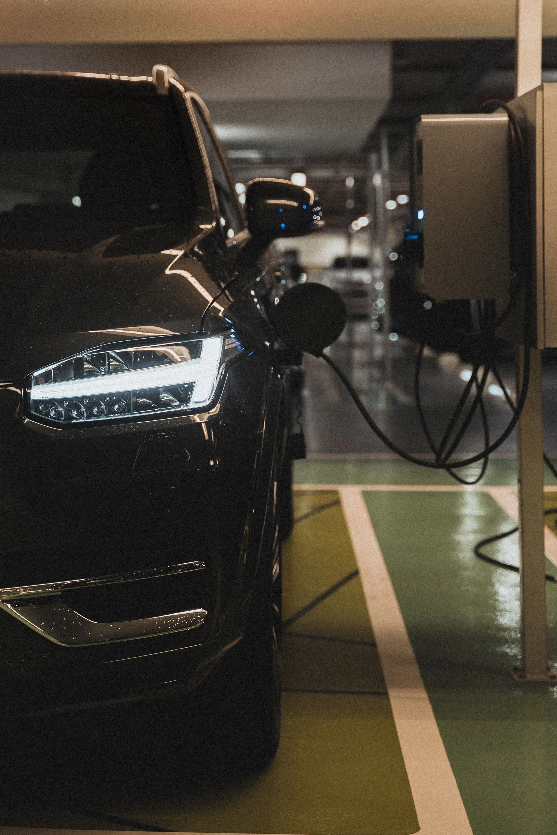 A black electric car charging at a station in a parking garage