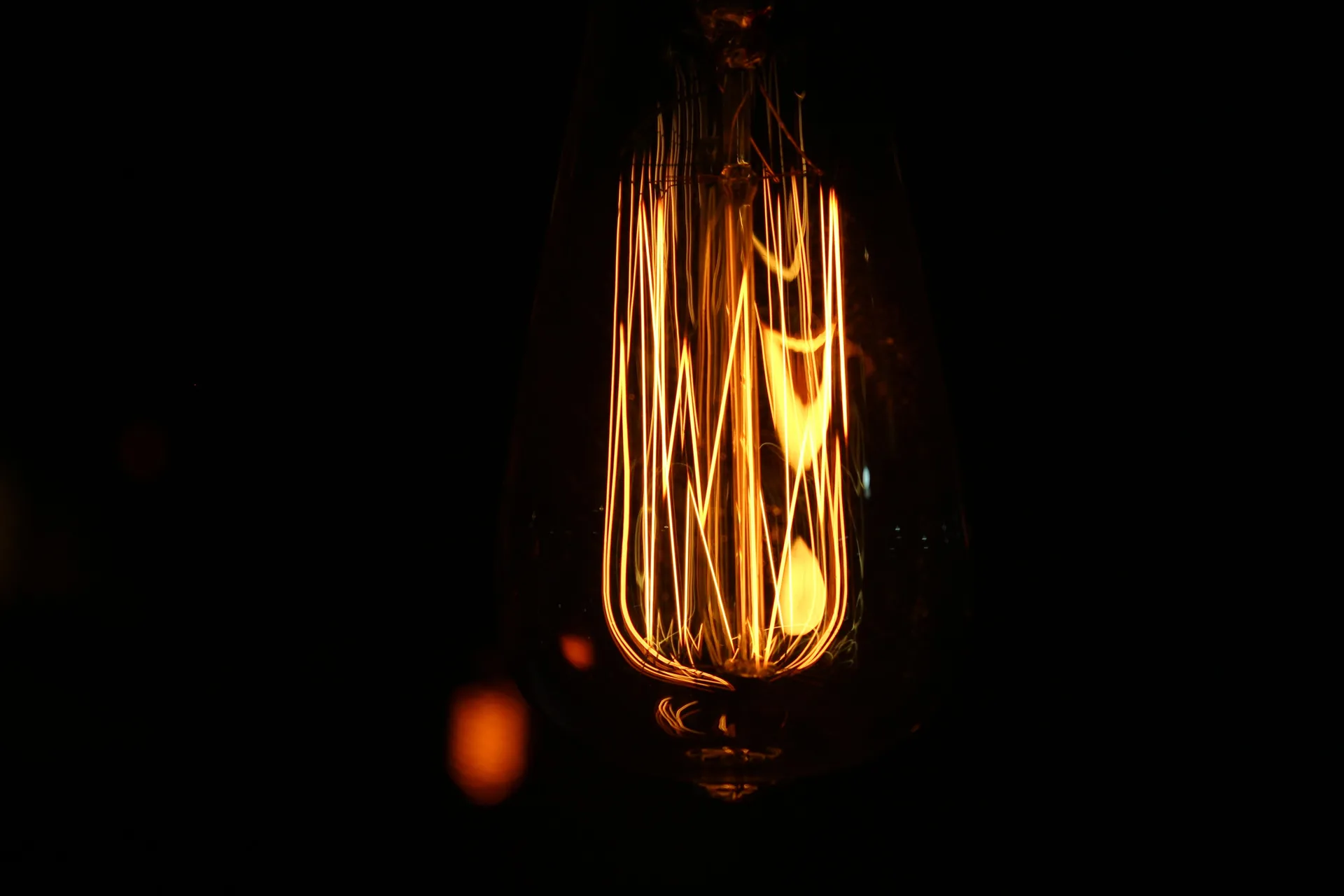A glowing vintage filament bulb against a dark background