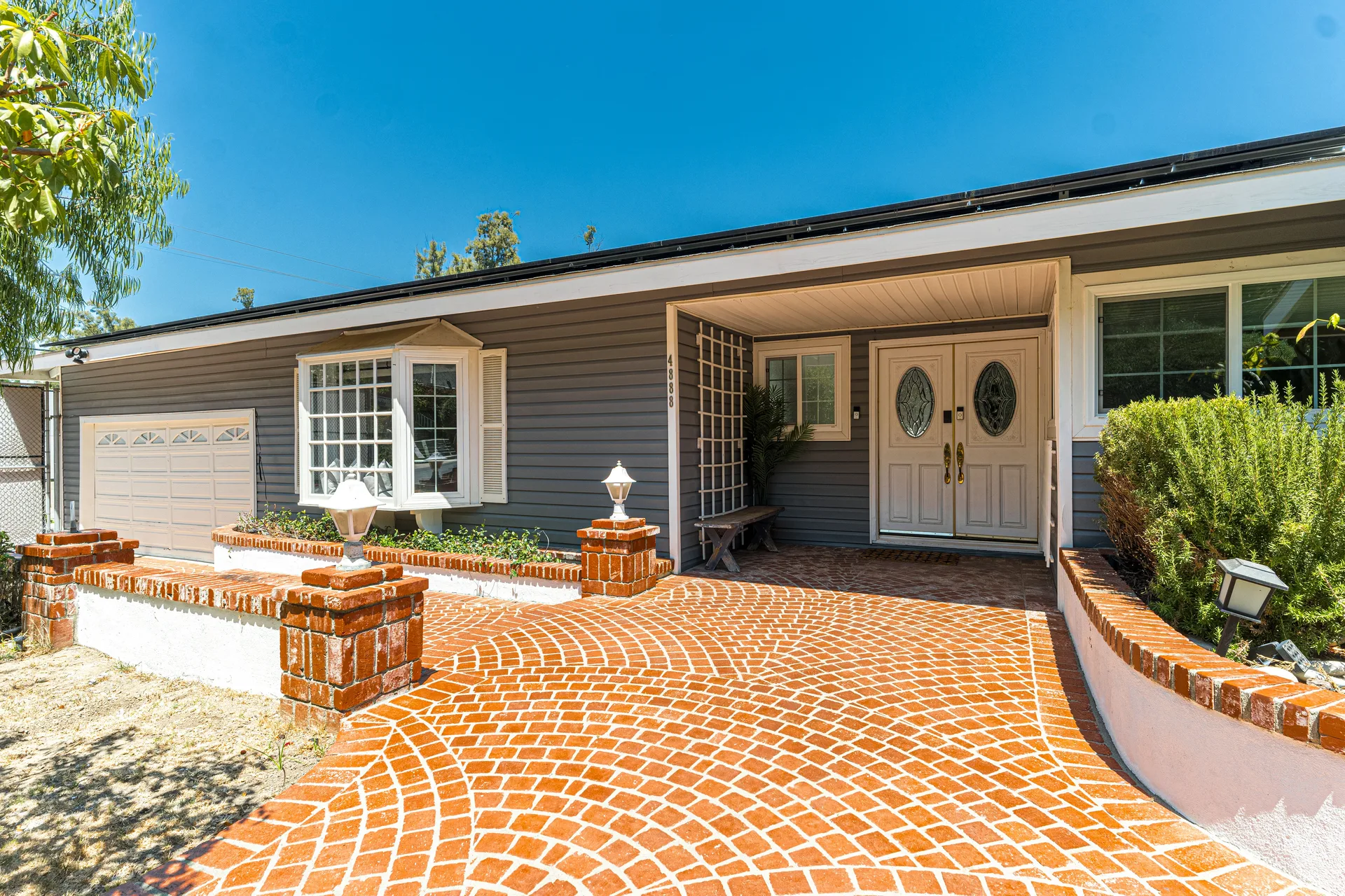 A suburban house with a brick driveway and patio