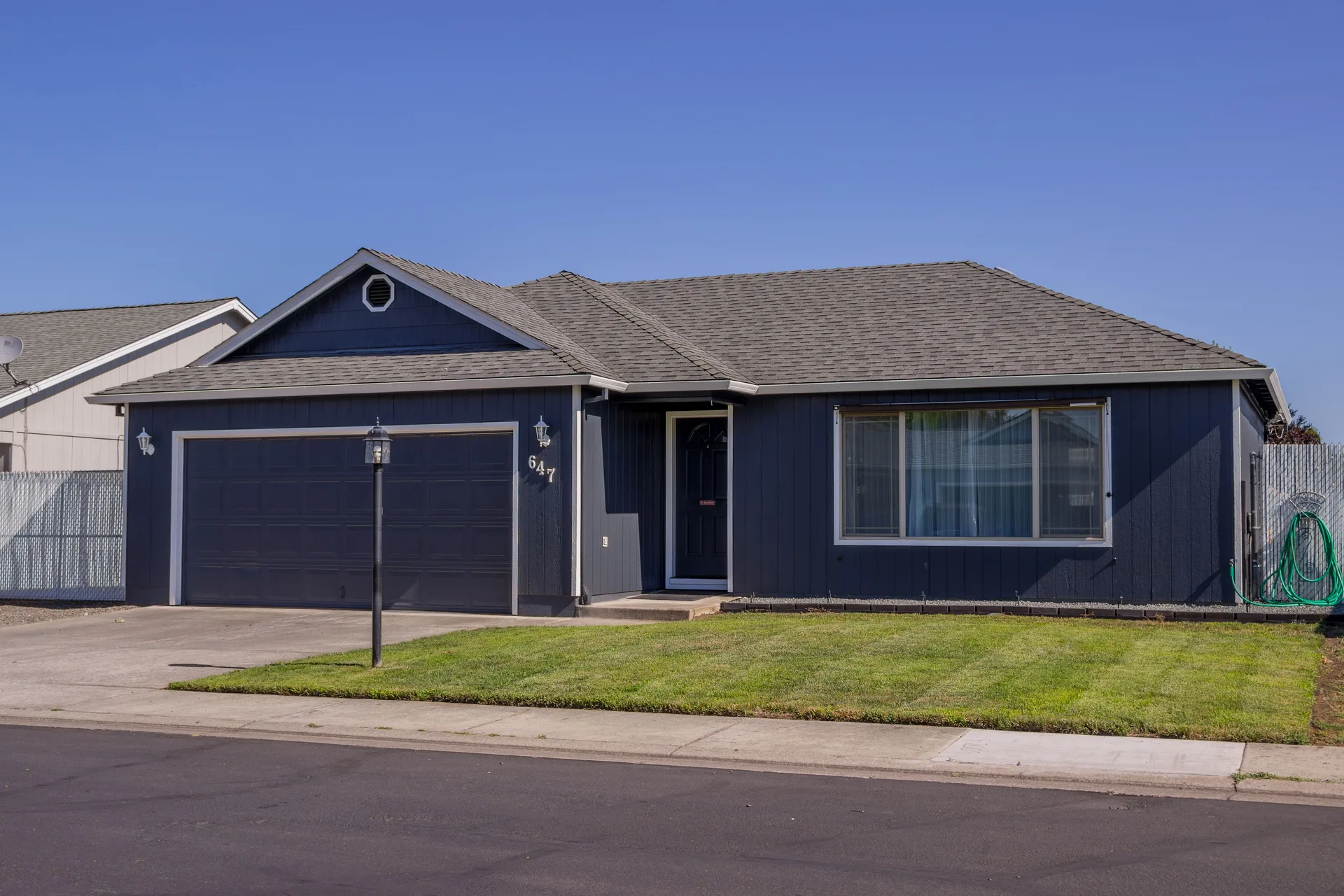 A suburban house with a driveway, garage, and lawn under a blue sky