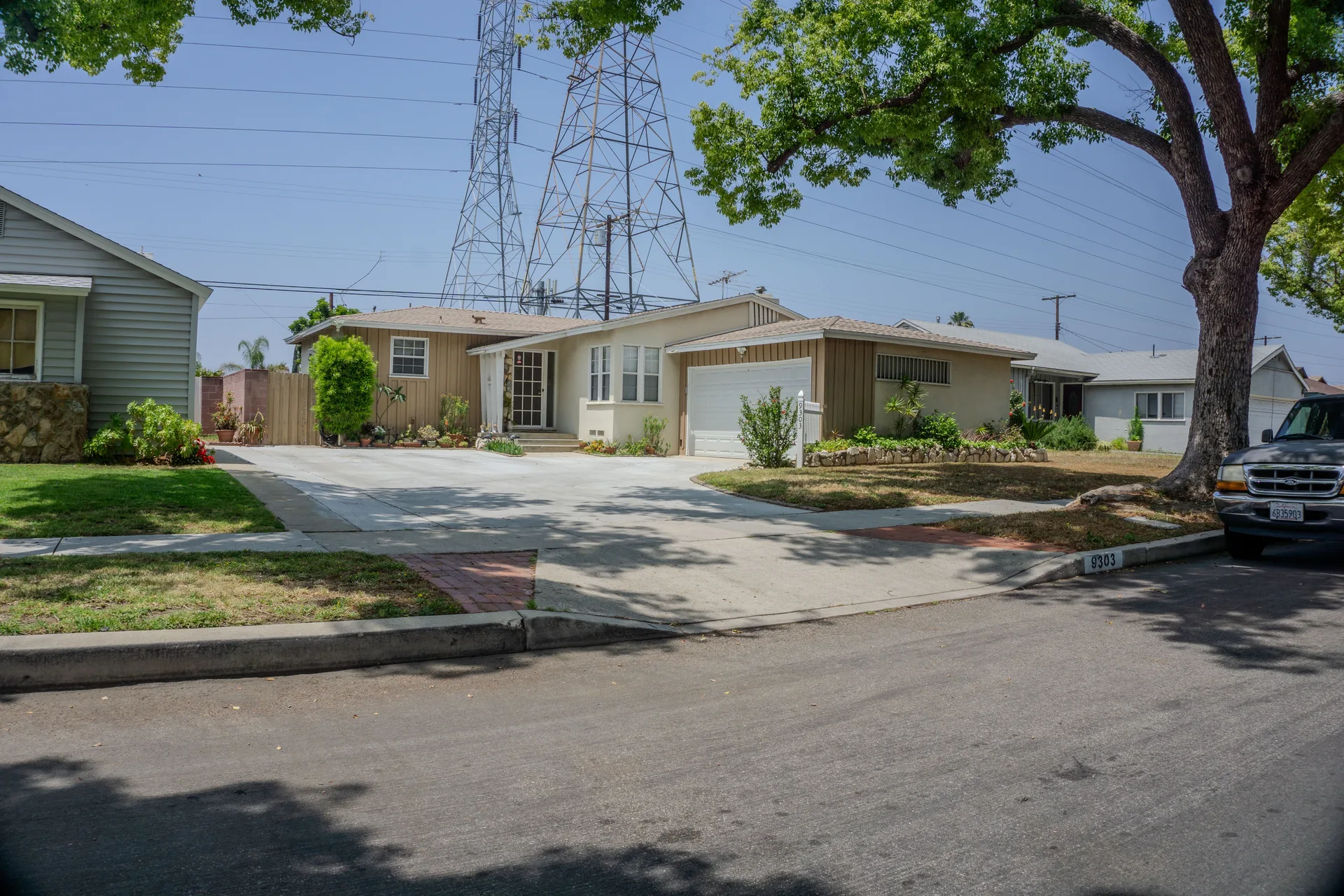 A suburban street with mid-century homes and greenery on a sunny day