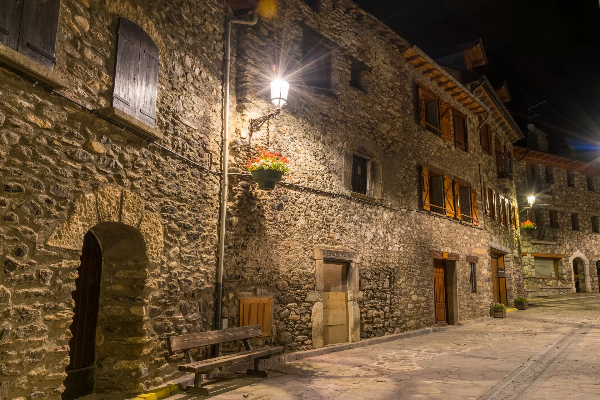 Stone buildings and street lamps lit at night