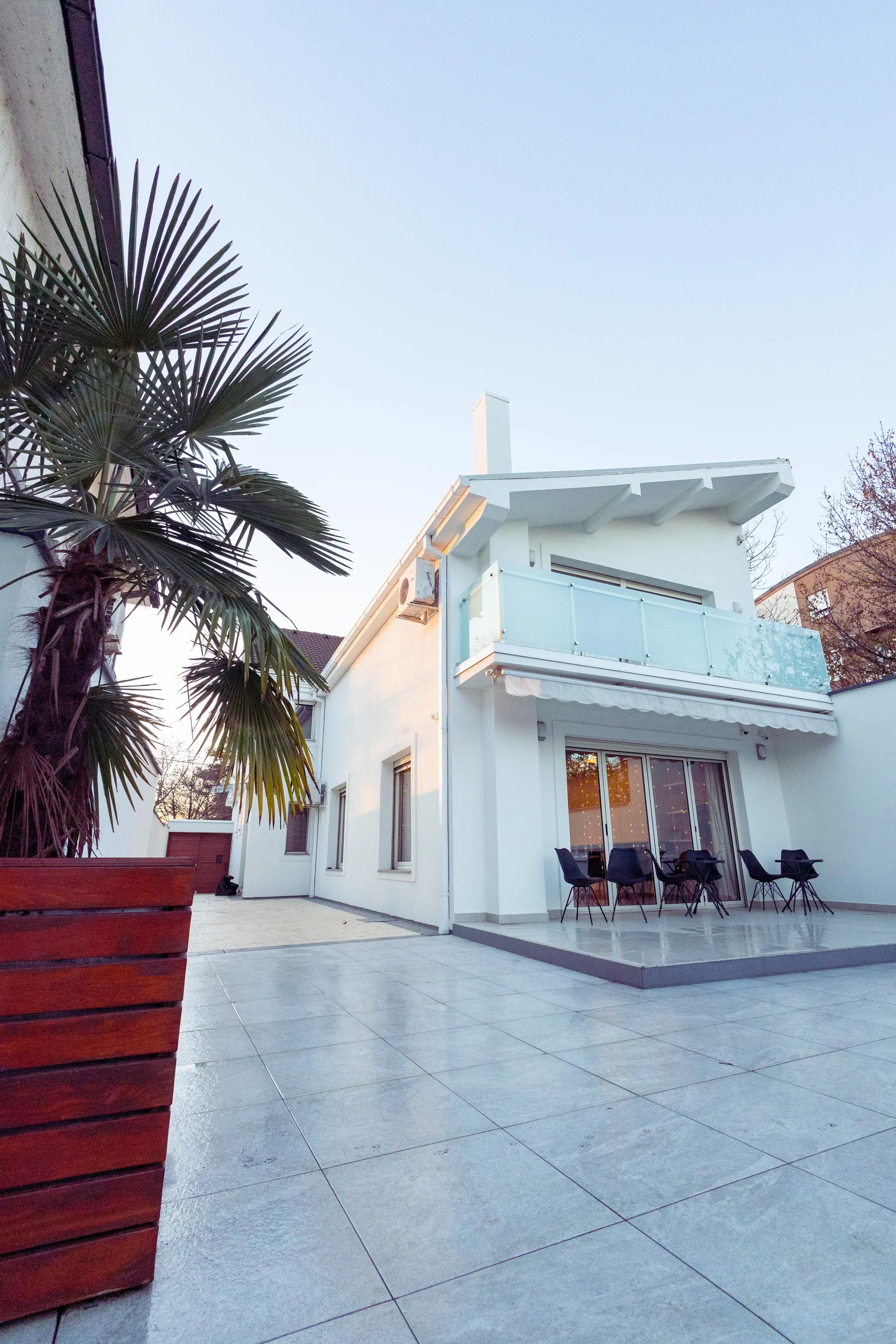 A modern white house exterior with palm trees and a patio