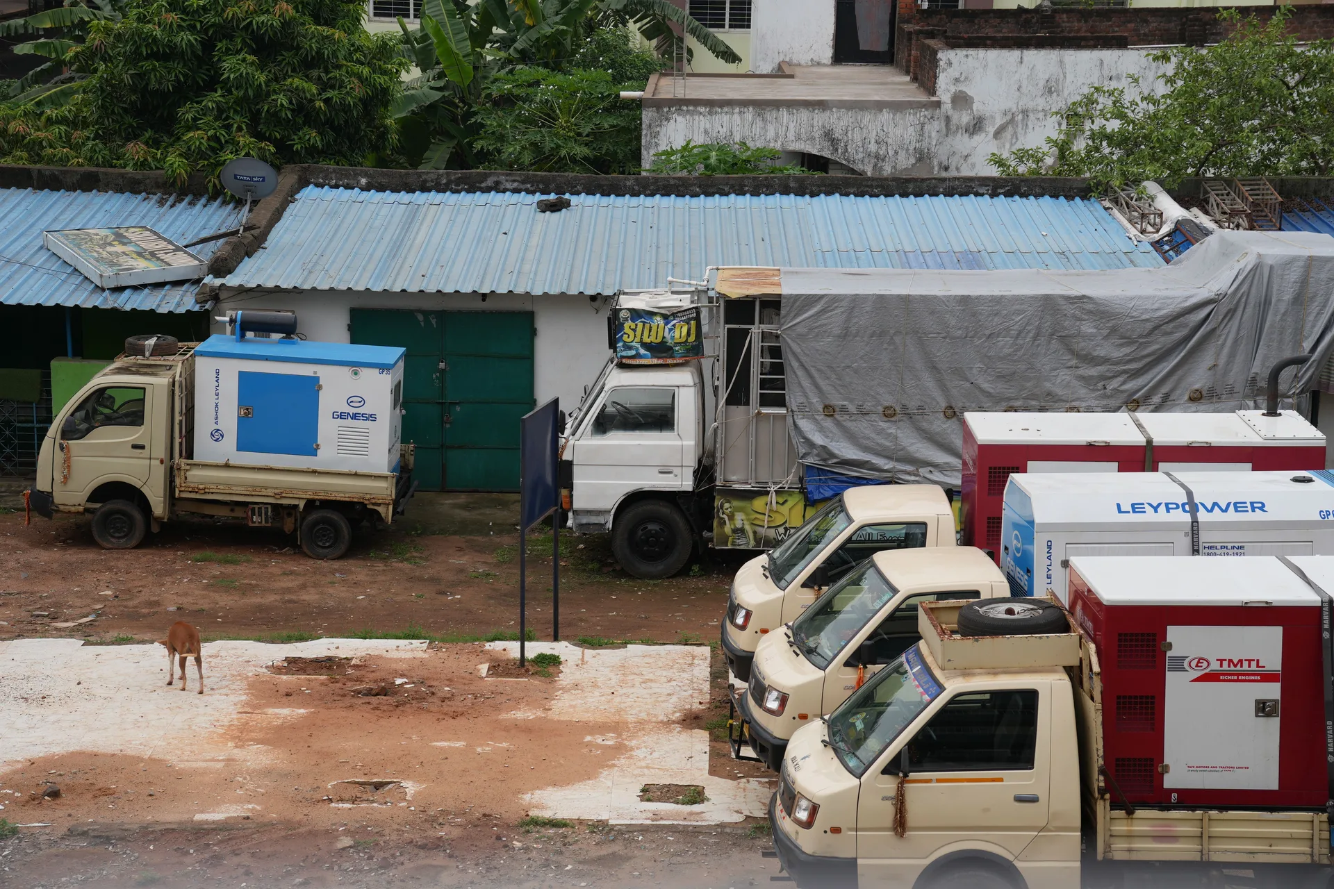 Row of utility trucks with generators parked beside a building outdoors