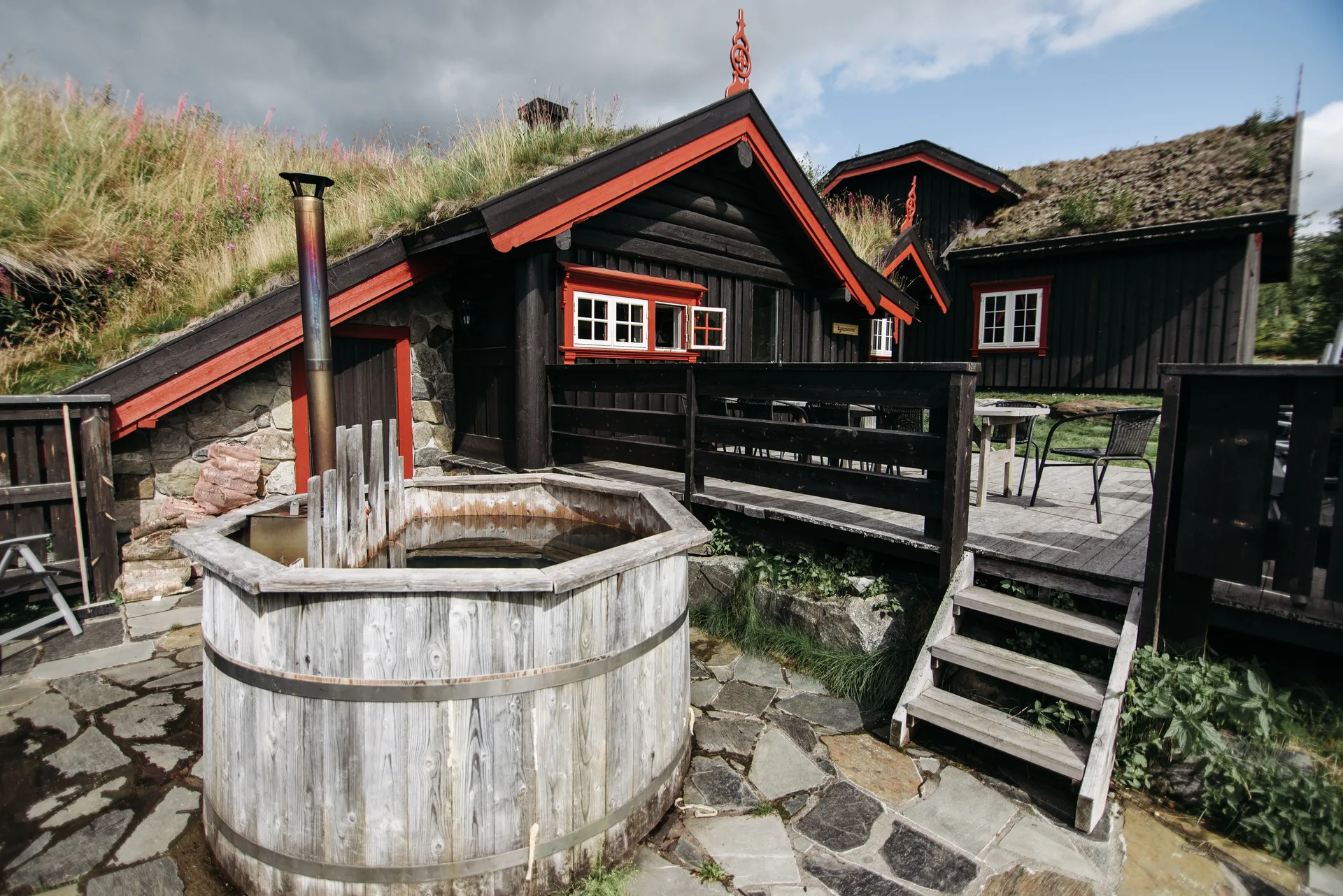 A wooden hot tub beside a rustic cabin outdoors