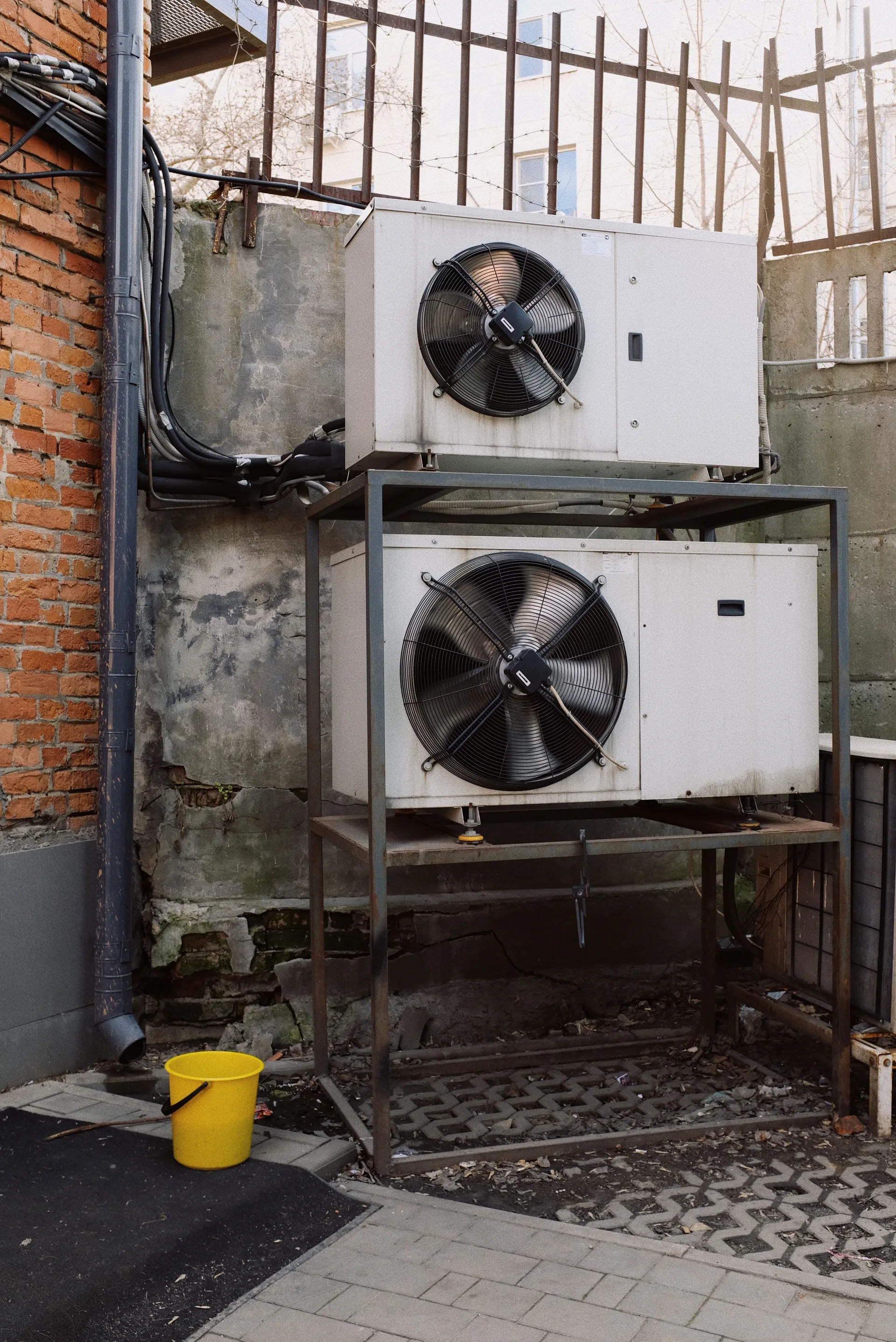 Two outdoor air conditioning units mounted on a brick wall