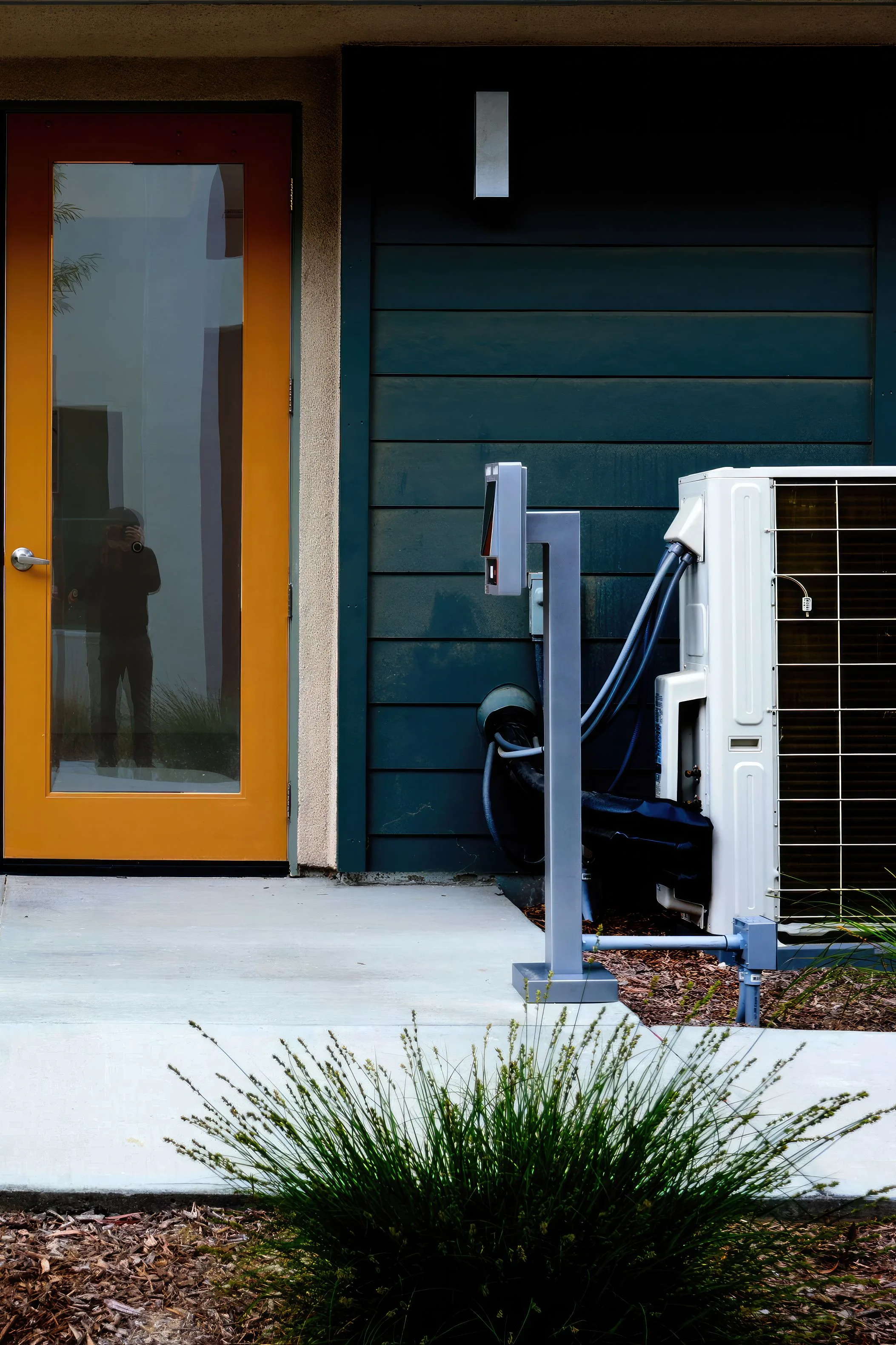 Modern house entrance with a yellow glass door and an outdoor air conditioning unit