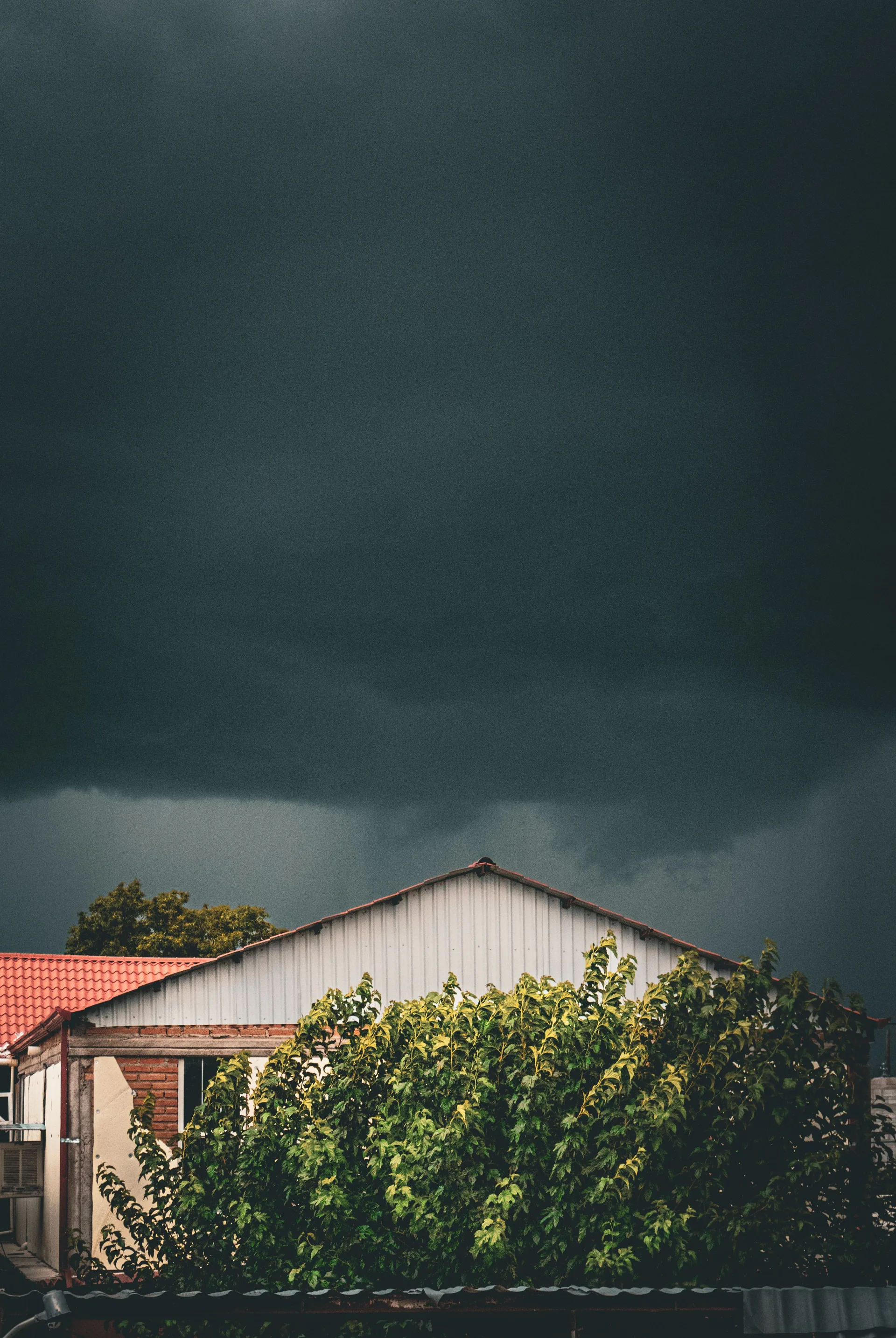 Dark storm clouds gathering over a house and trees
