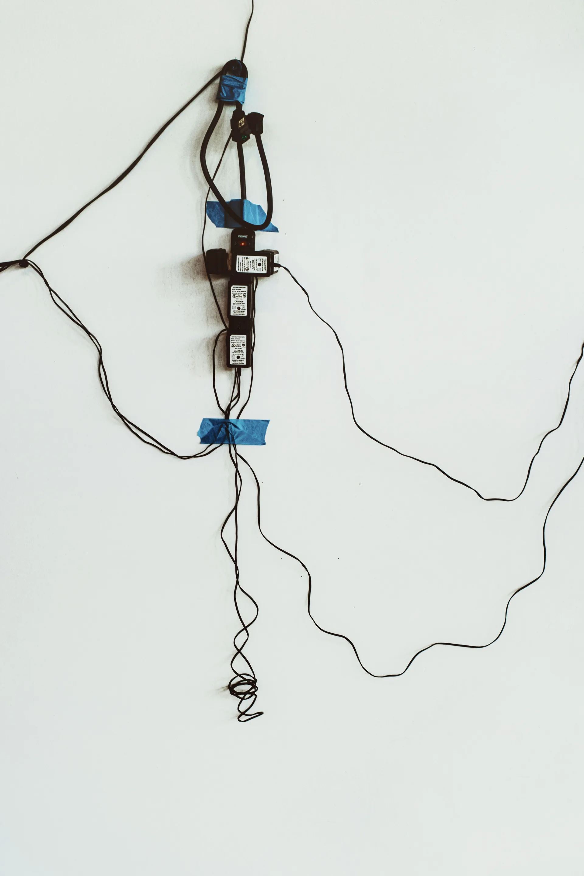 Tangled cables and multiple power sockets taped to a wall