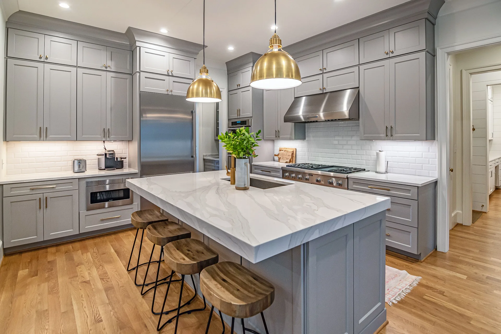 A modern kitchen with gold pendant lights over a large island