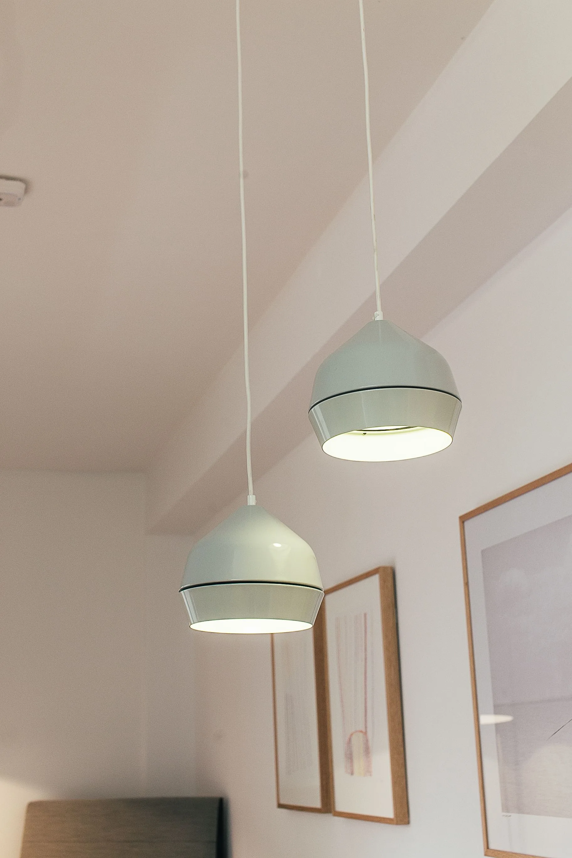 Round pendant lamps hanging from a white ceiling in a bright room