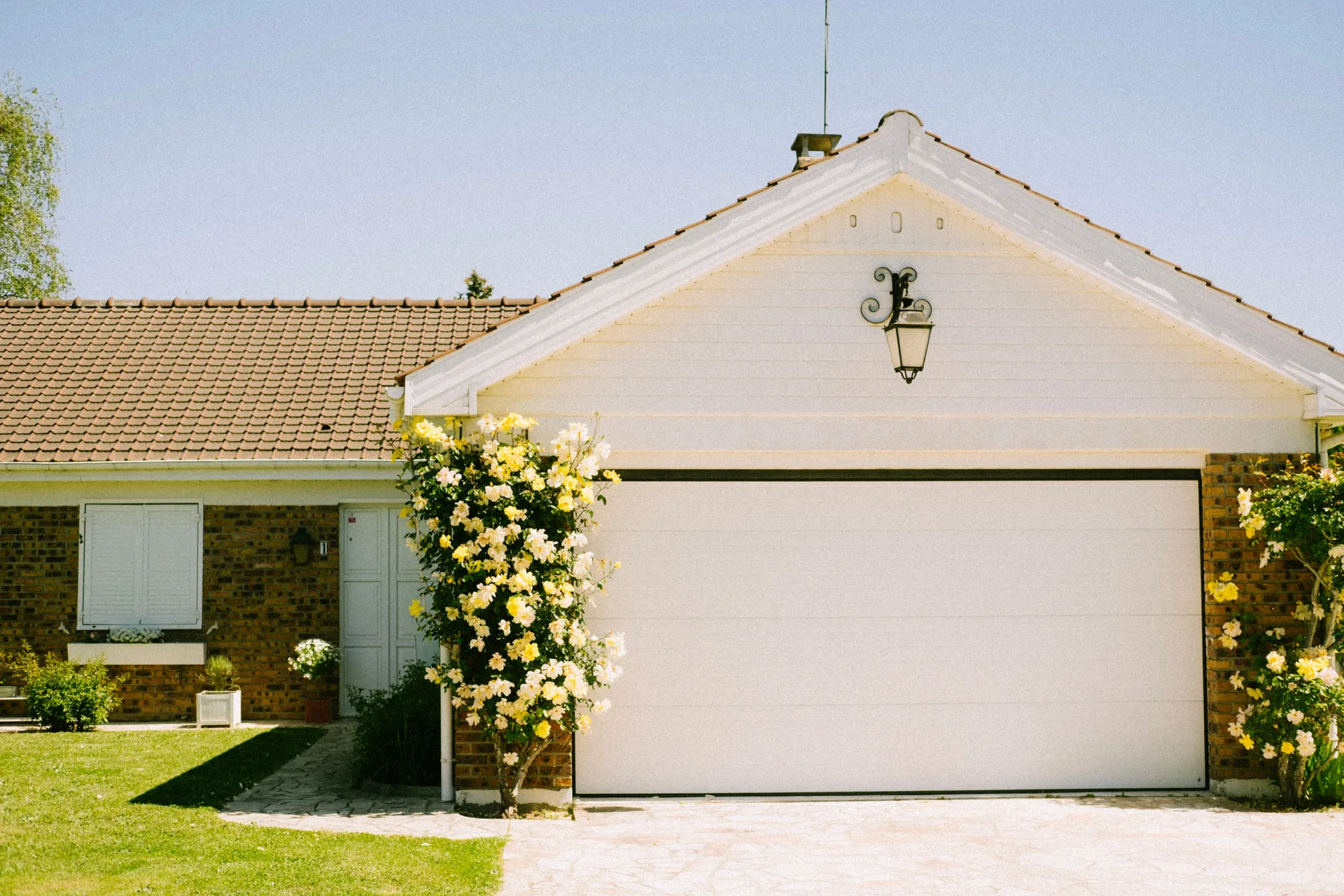 Suburban home with a garage and flowering plants beside the driveway