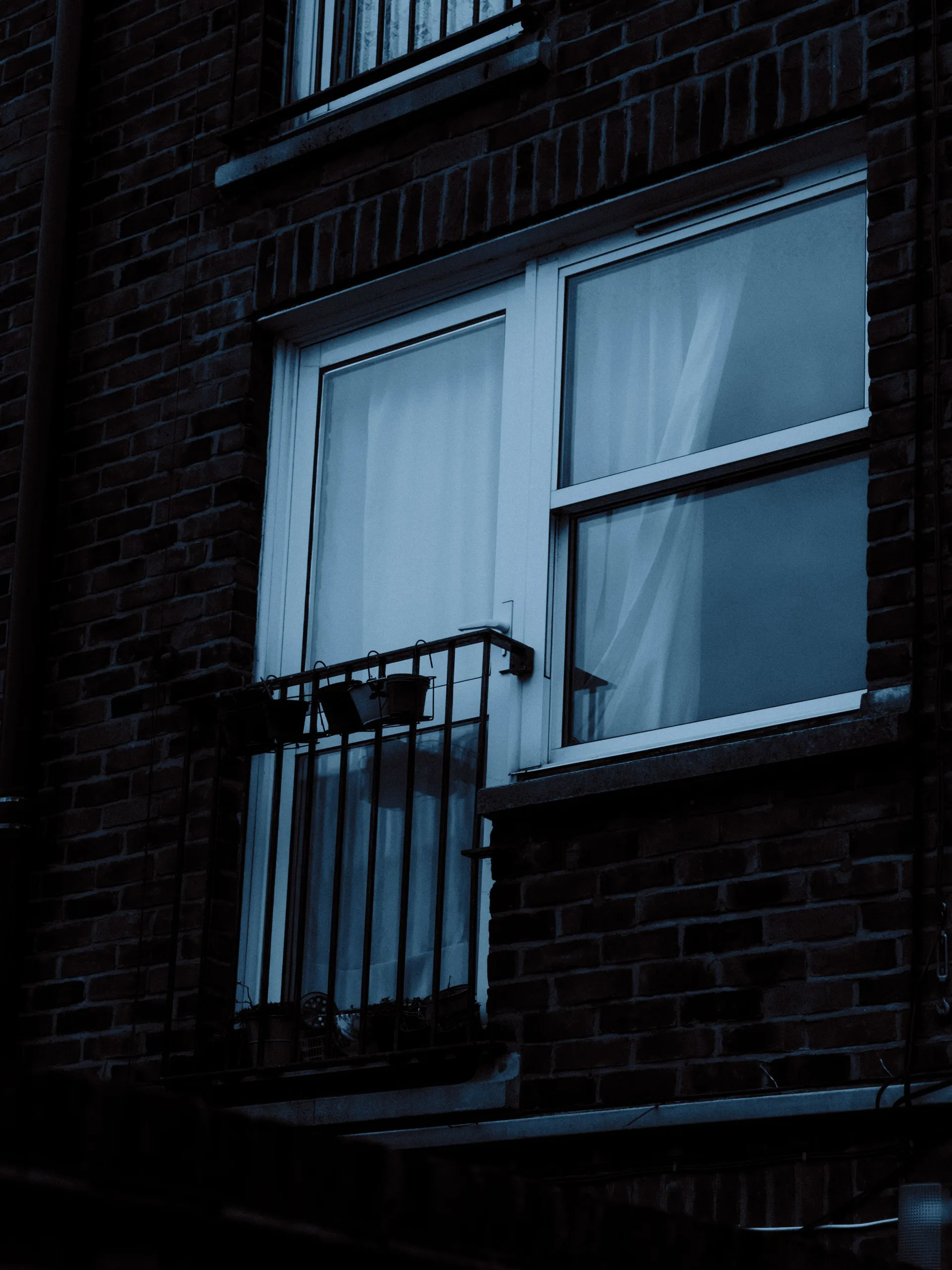 Dark apartment building window with curtains at night