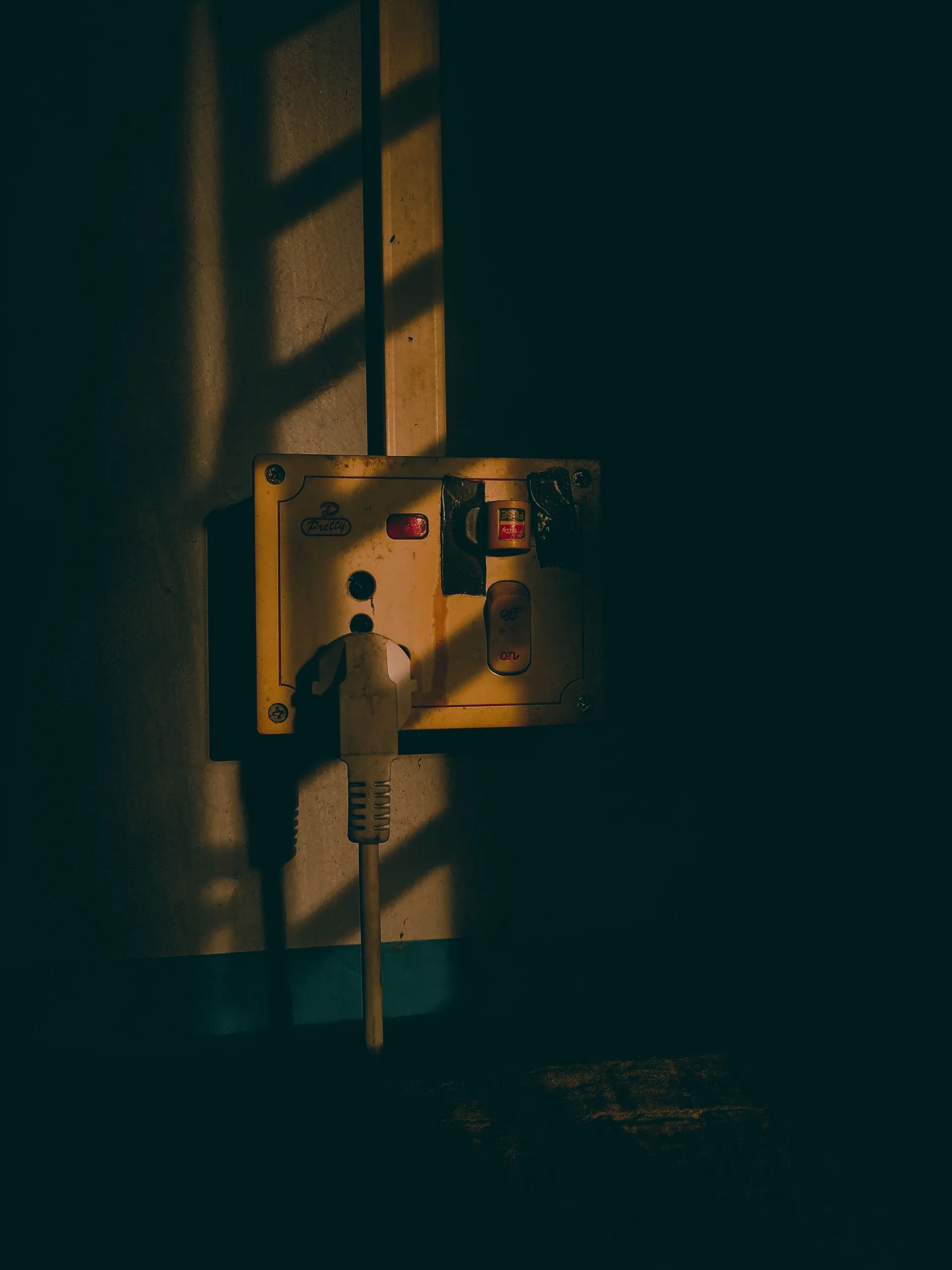 An electrical outlet on a wall with dramatic shadows