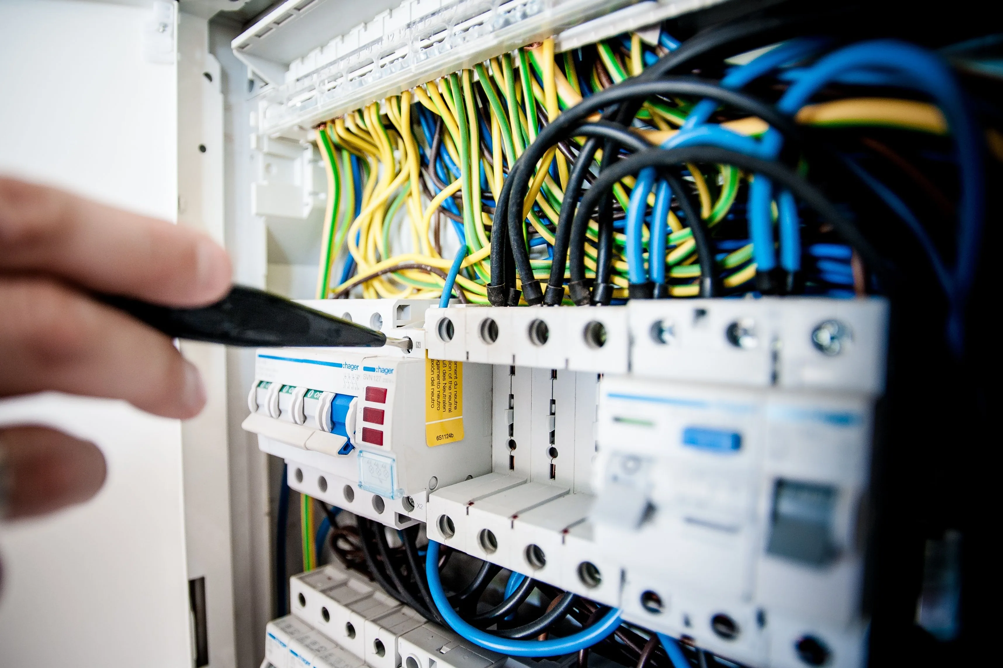 Hands working on wiring inside an open circuit breaker panel