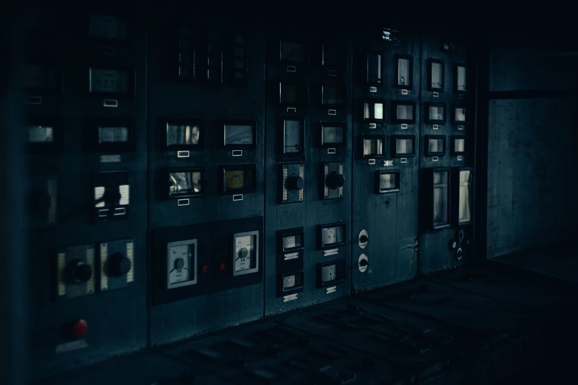 A dark, retro industrial control panel with dials and gauges in a maintenance room