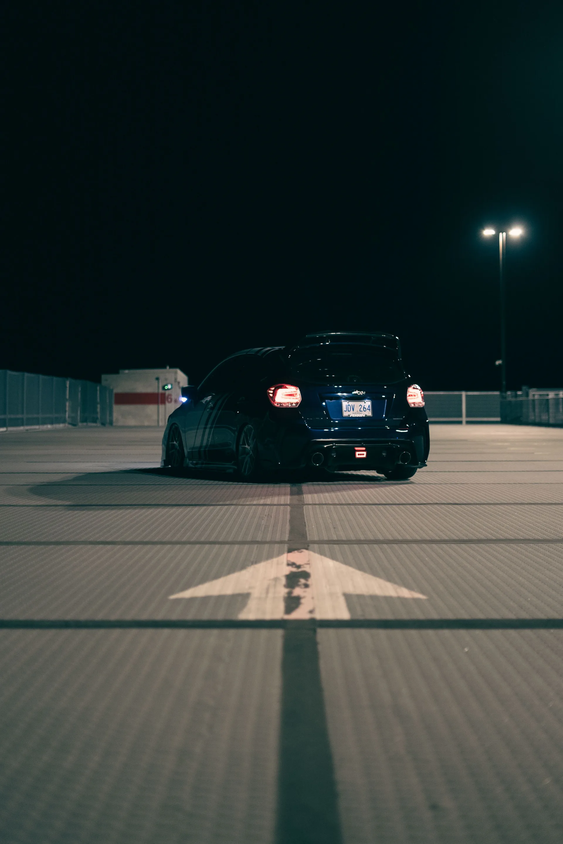 A car parked in an empty parking lot at night