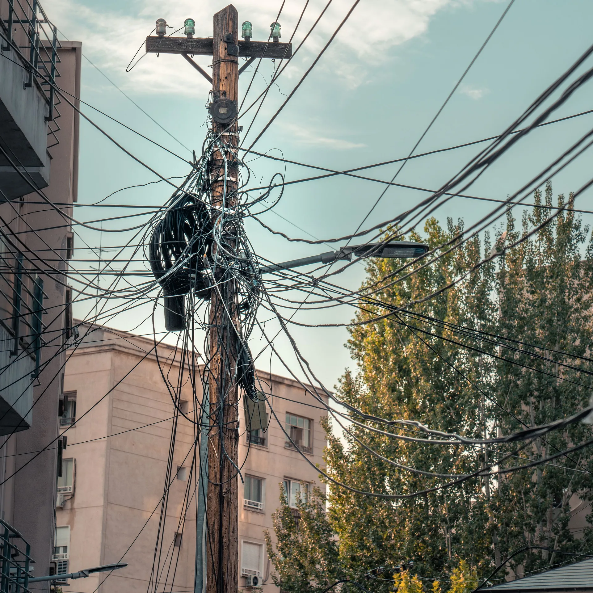 Tangled power lines and cables on a city utility pole