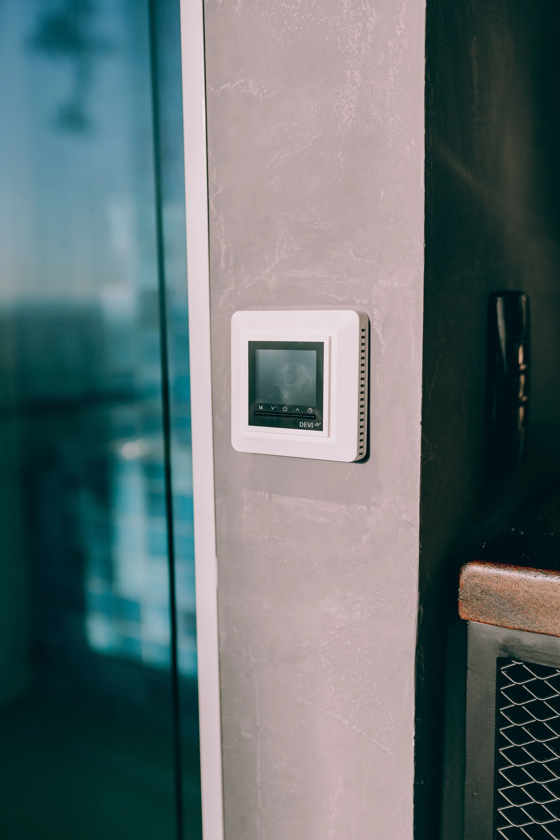 A digital smart thermostat mounted on a concrete wall