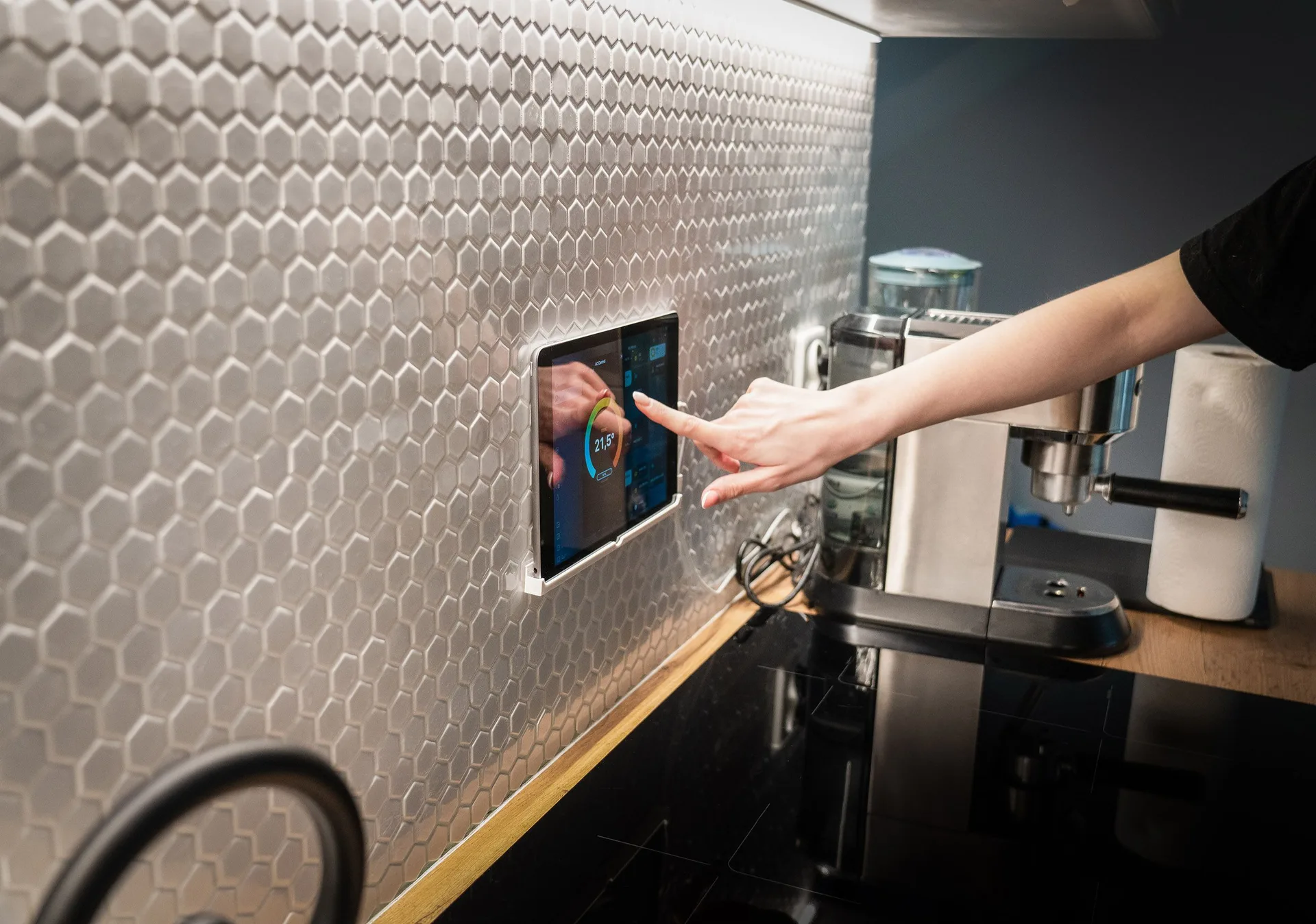 A touchscreen smart home control panel on a kitchen wall