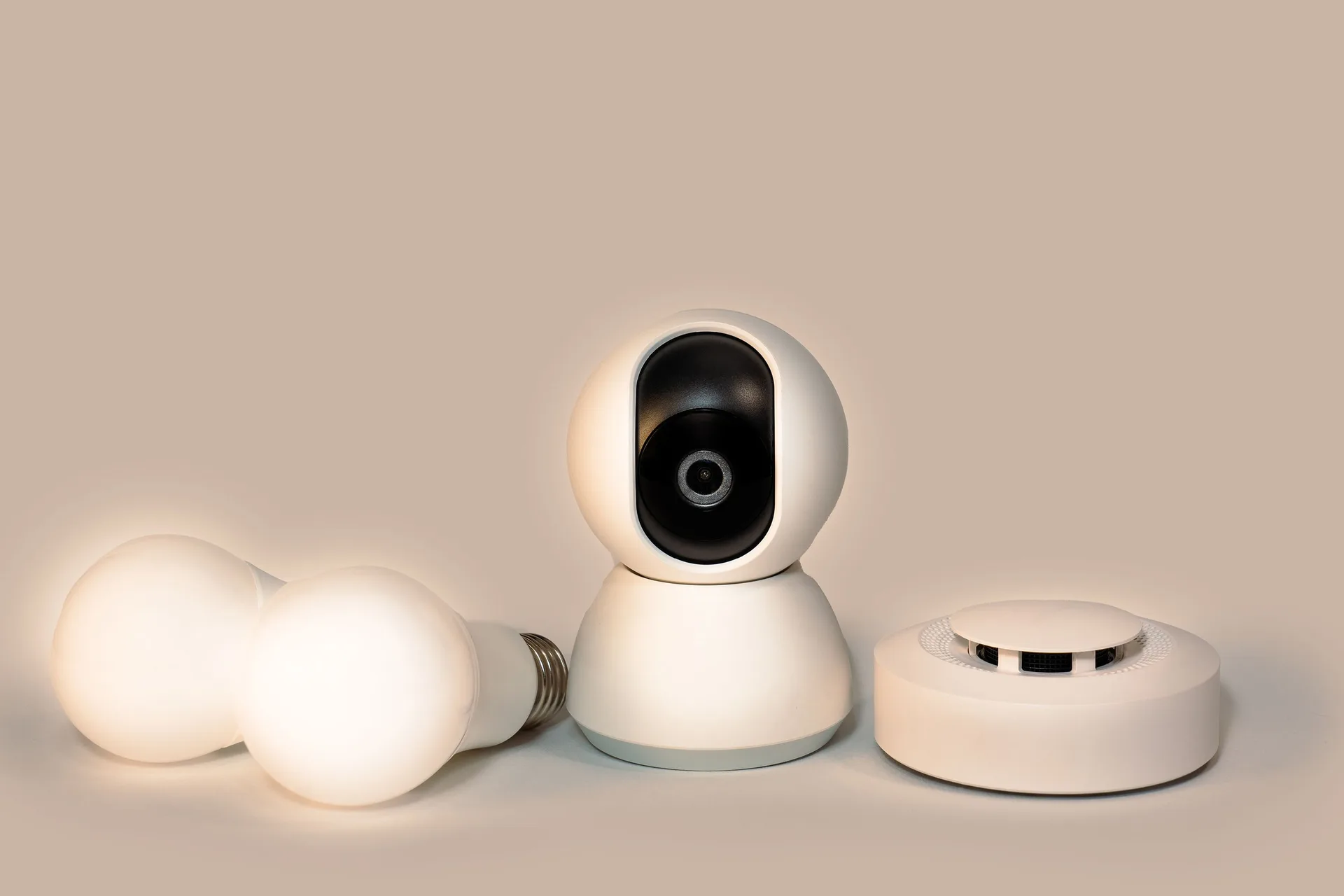 A set of smart home gadgets including a smoke detector, camera, and bulbs