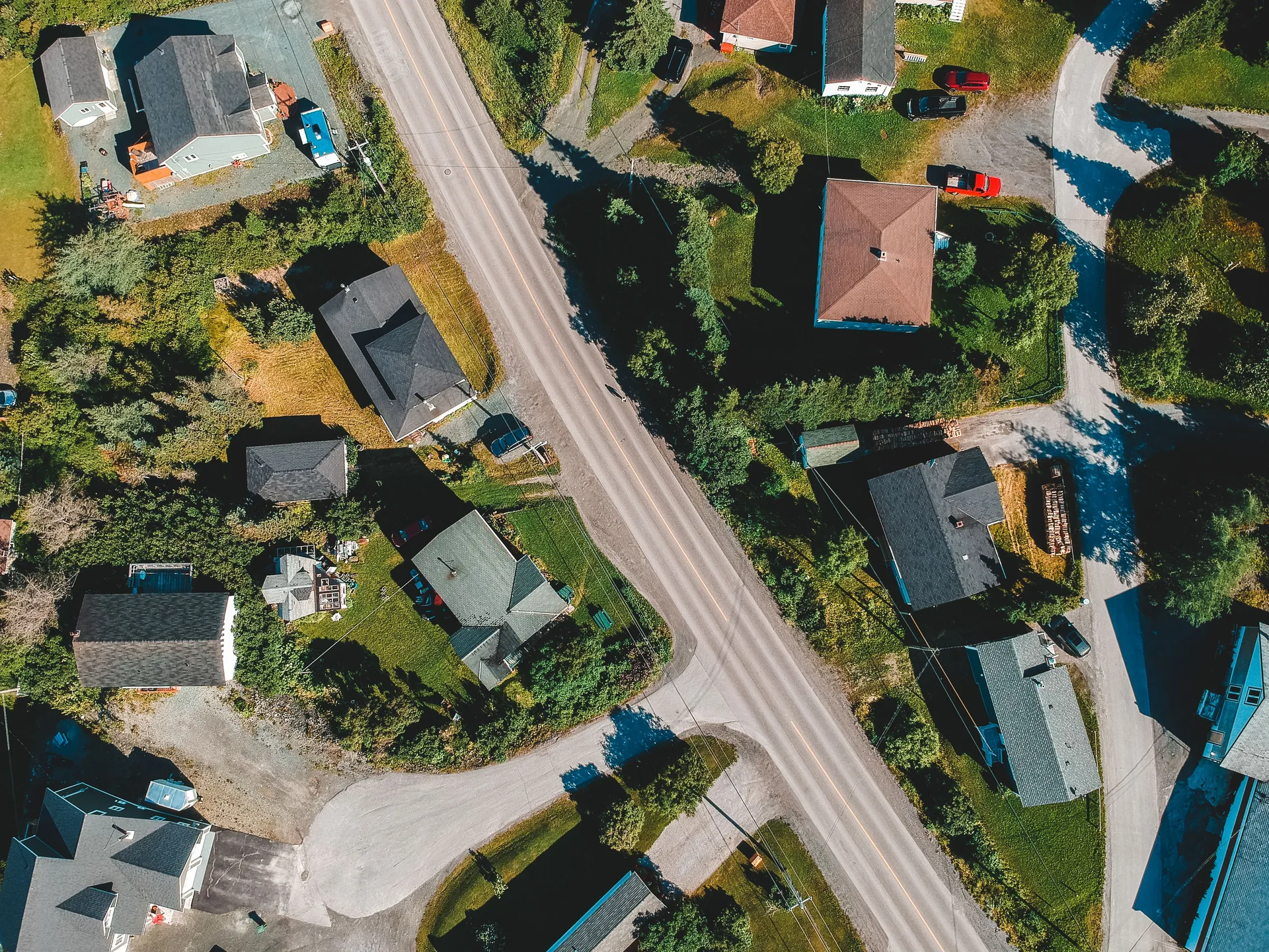 Aerial view of house rooftops along a roadway in a green valley setting