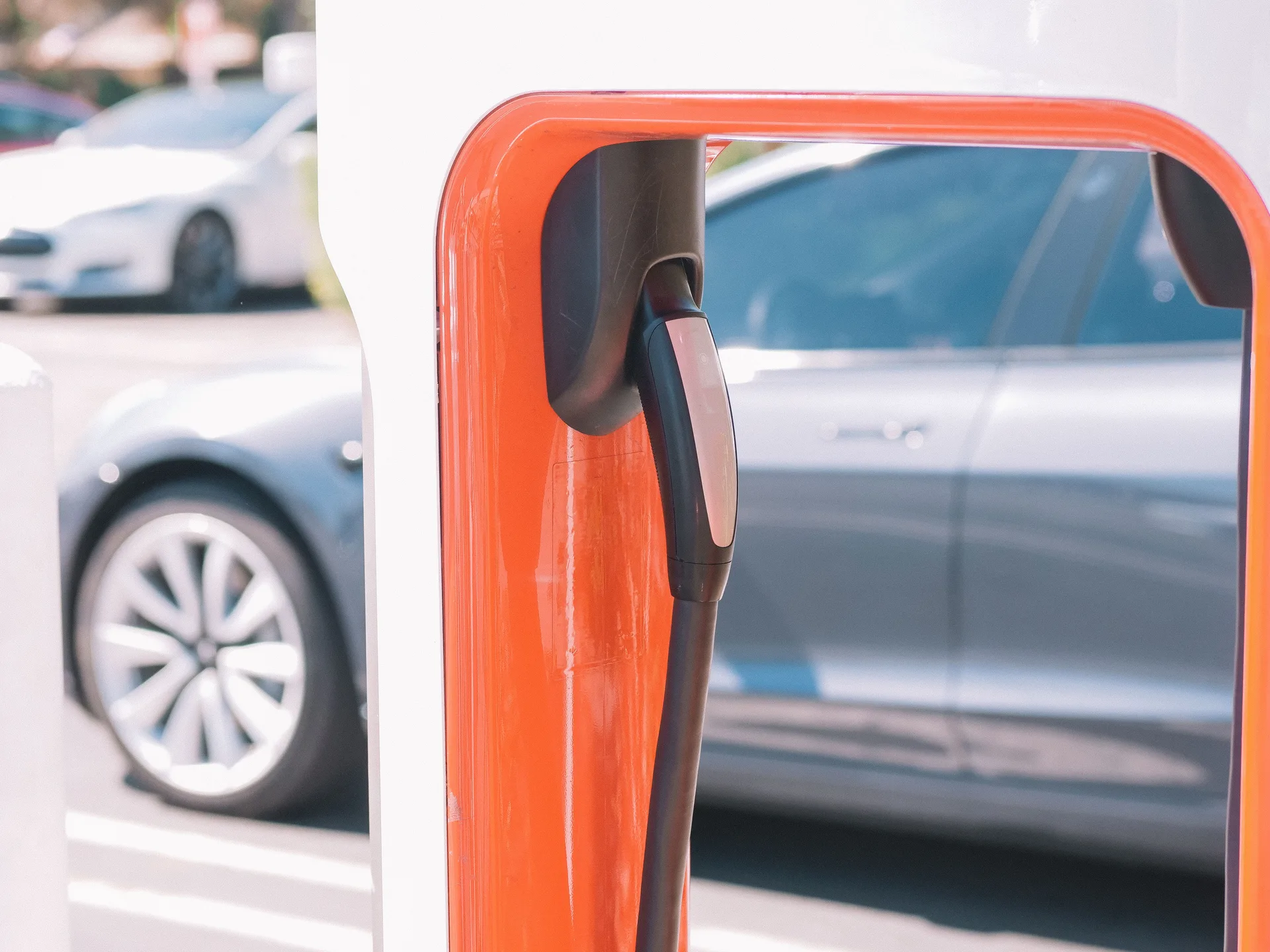 Close-up of an electric vehicle charger with a car behind it