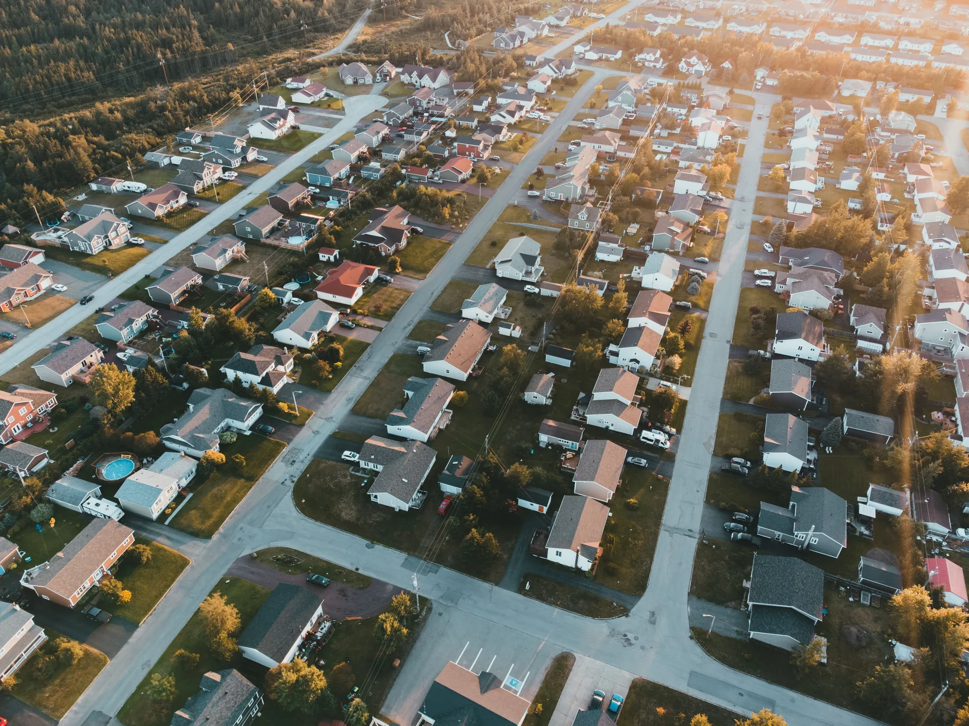 Aerial view of a suburban neighborhood at sunset with rows of houses and streets