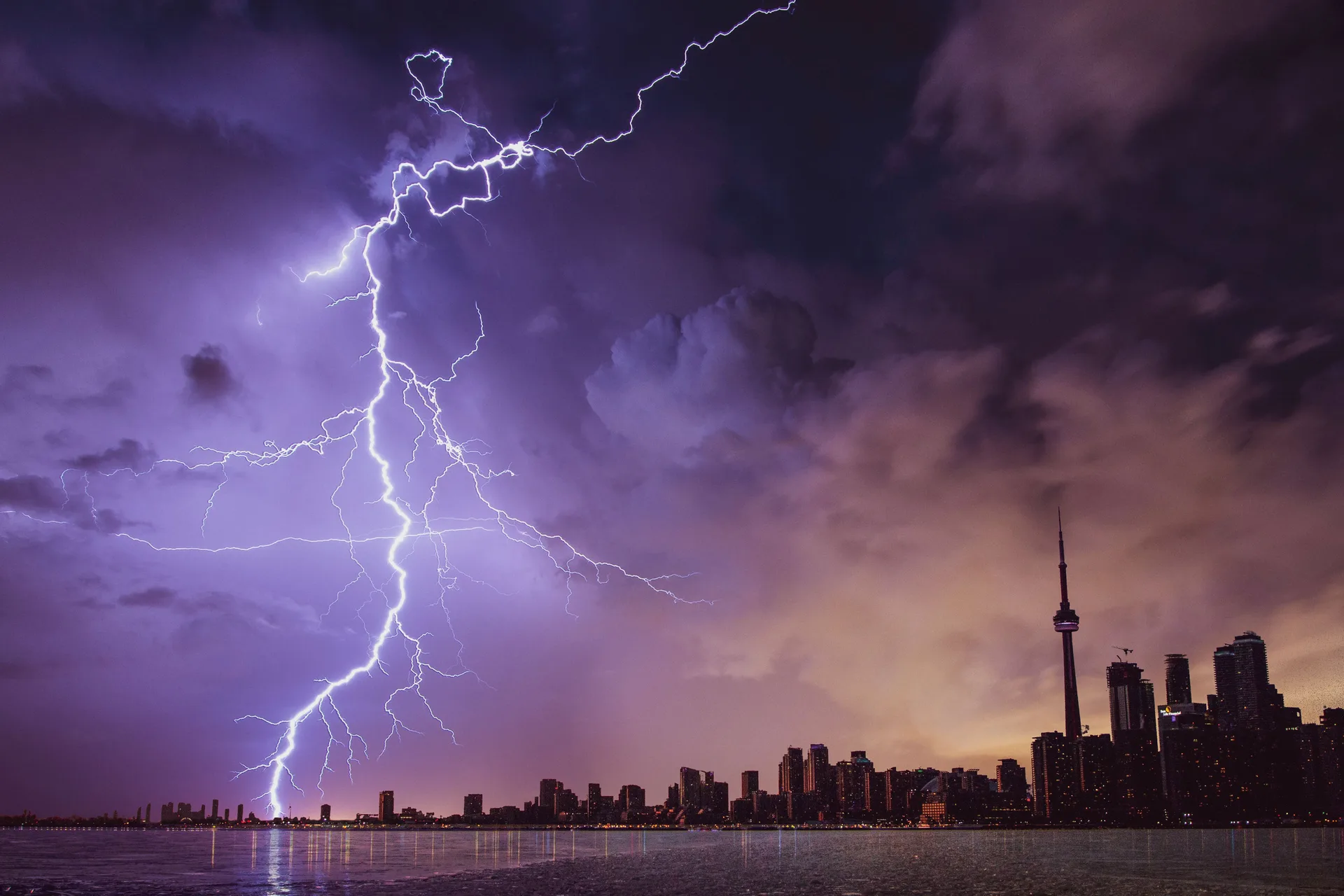 Lightning bolt over a city skyline under storm clouds