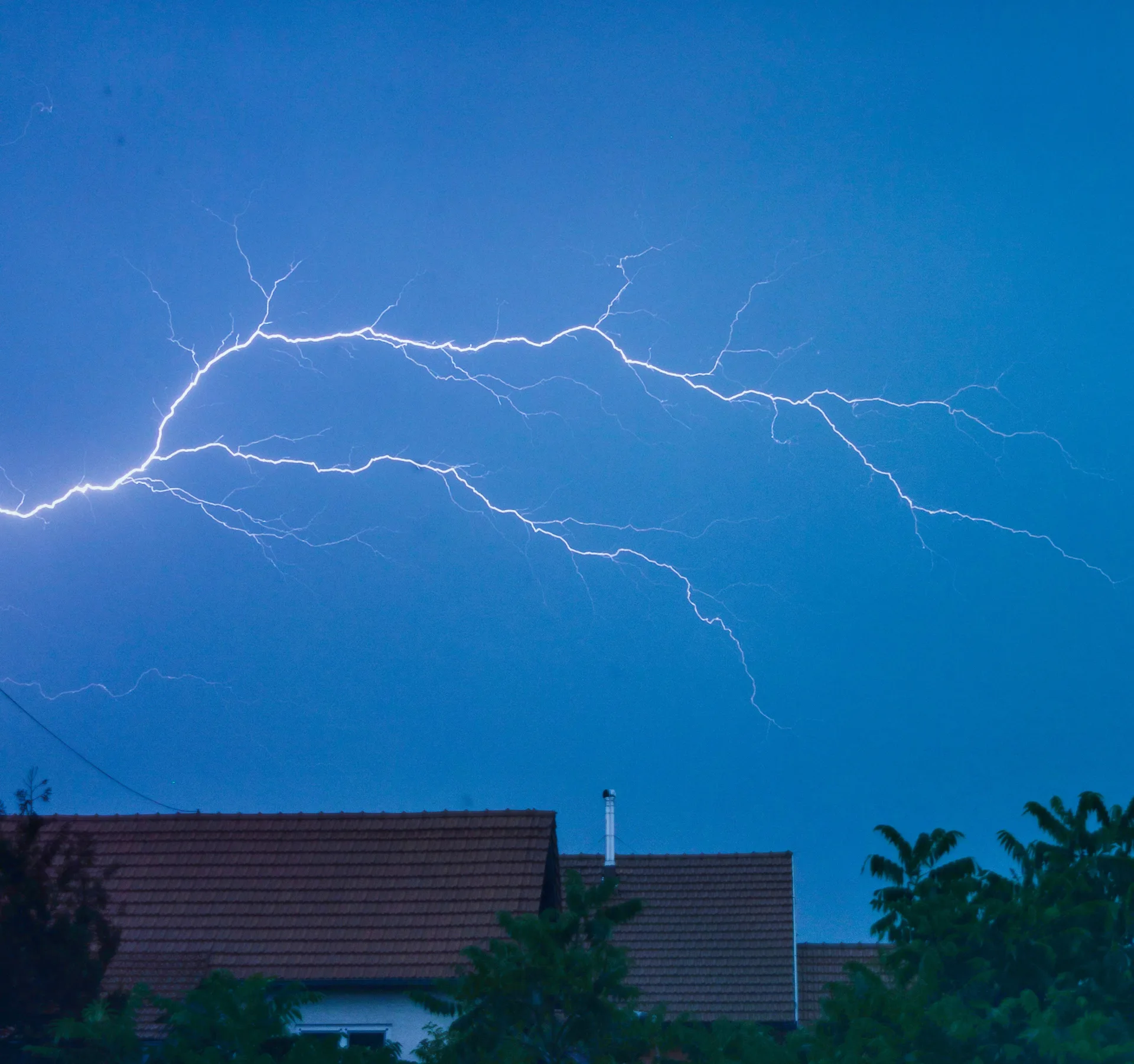 Lightning bolt in the night sky over suburban rooftops